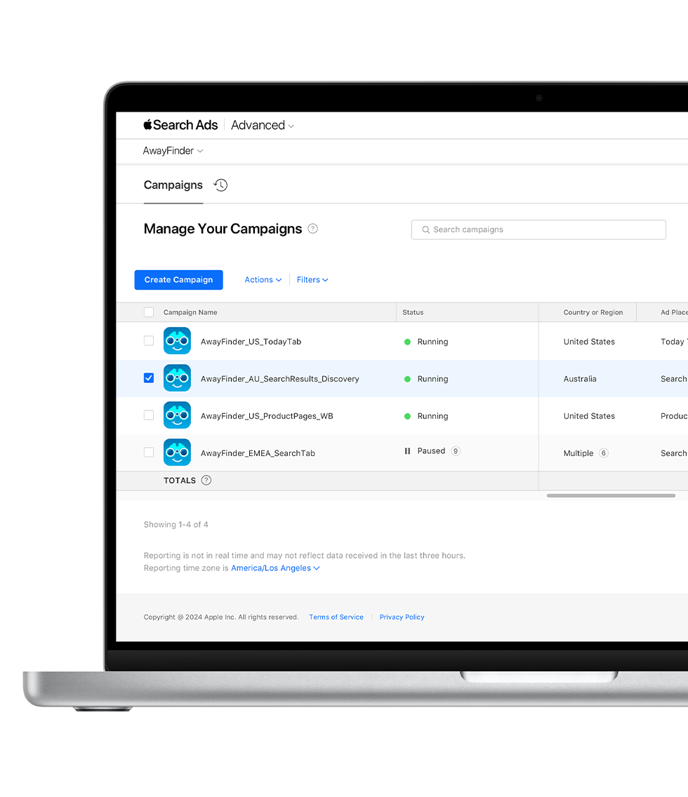 A MacBook is open to the Campaigns dashboard in Apple Ads Advanced. Four campaigns are listed with their campaign name, status, country or region, and ad placement appearing in columns.