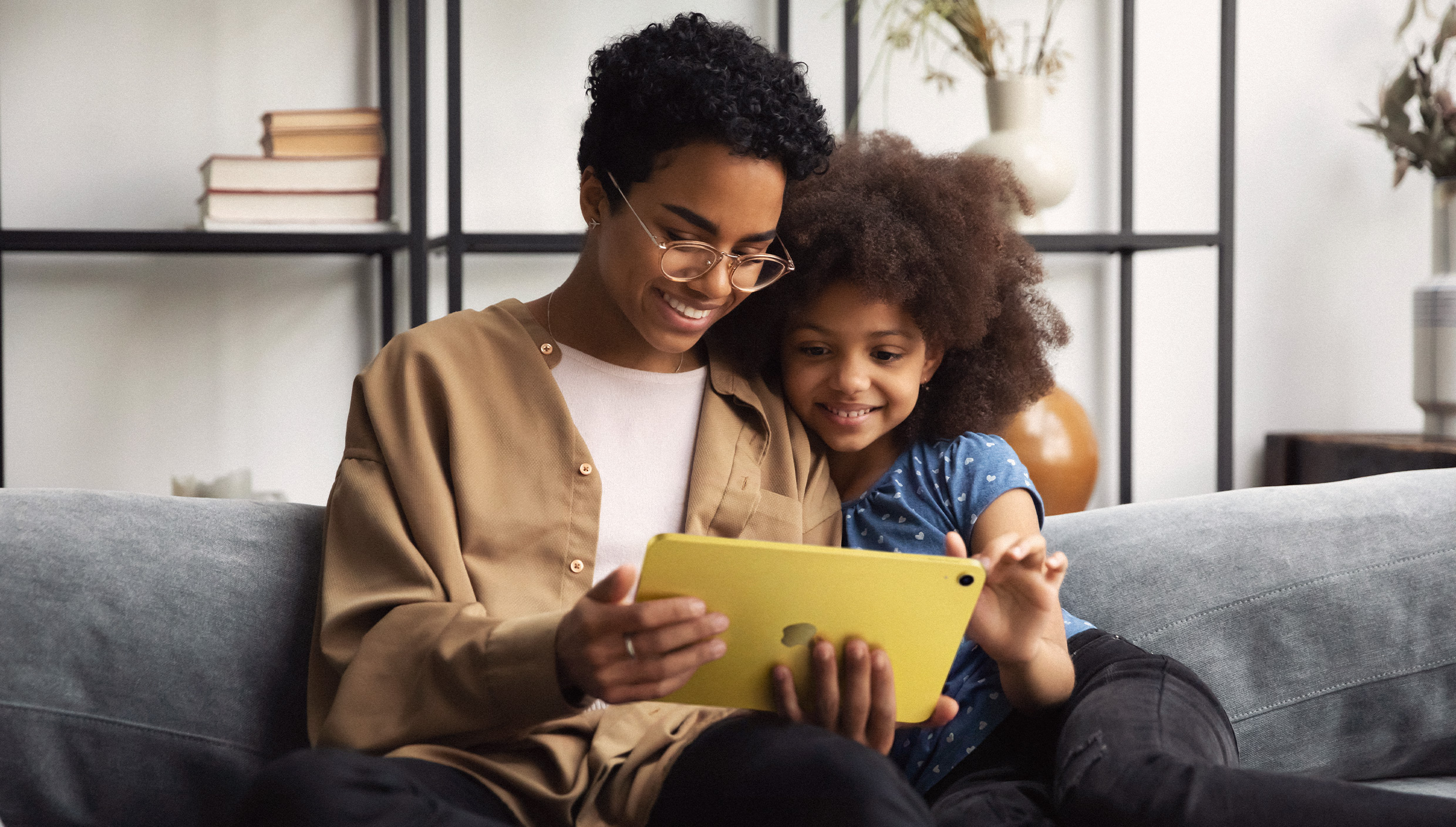 ソファに座り、一緒にiPadを見ている大人と子供。