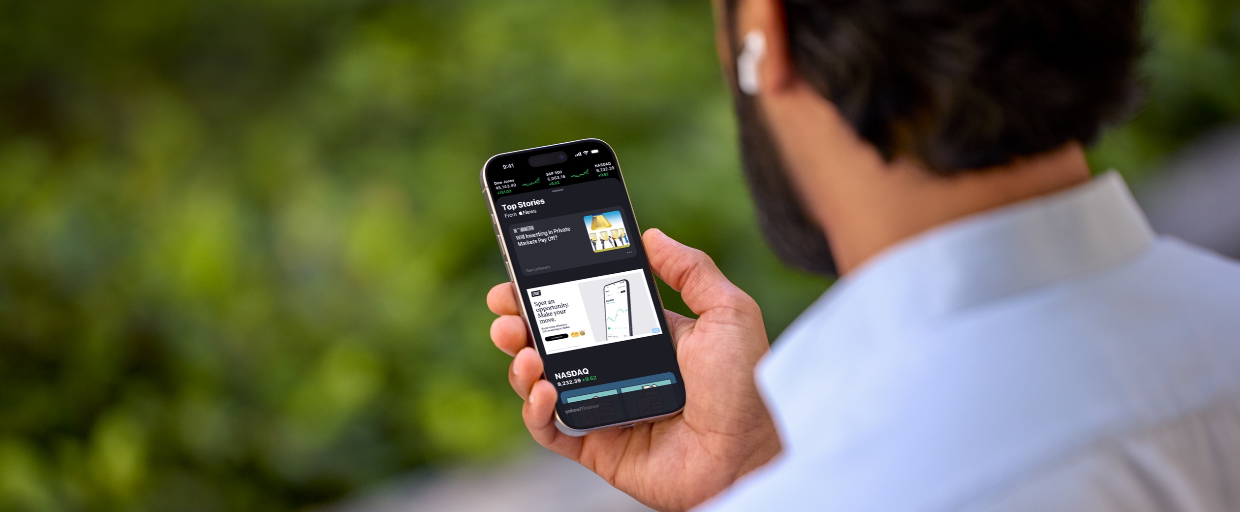 A person looks at the Stocks app on an iPhone that features a Stake ad.