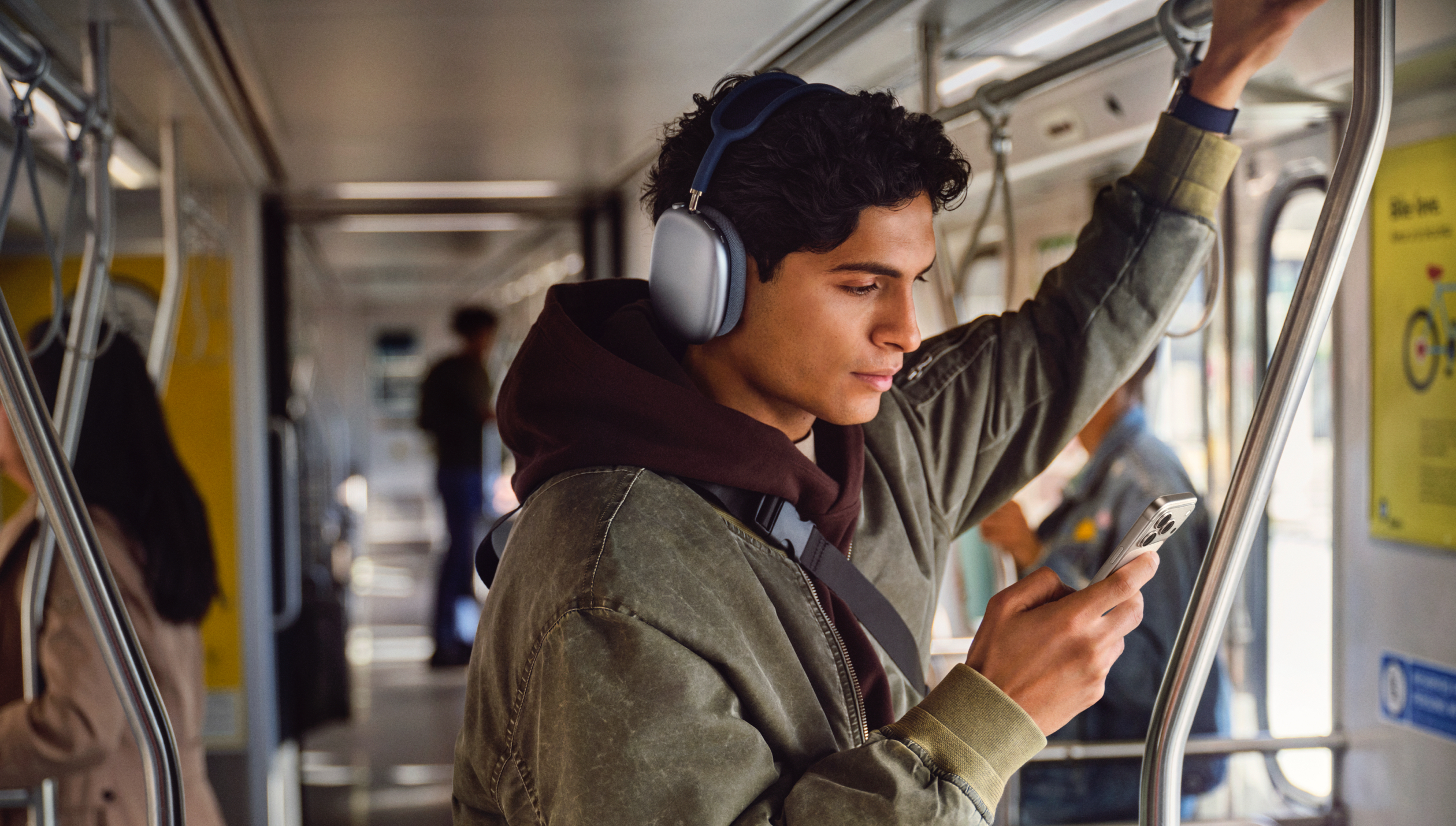 Человек держится за поручень в электричке и смотрит на экран iPhone.