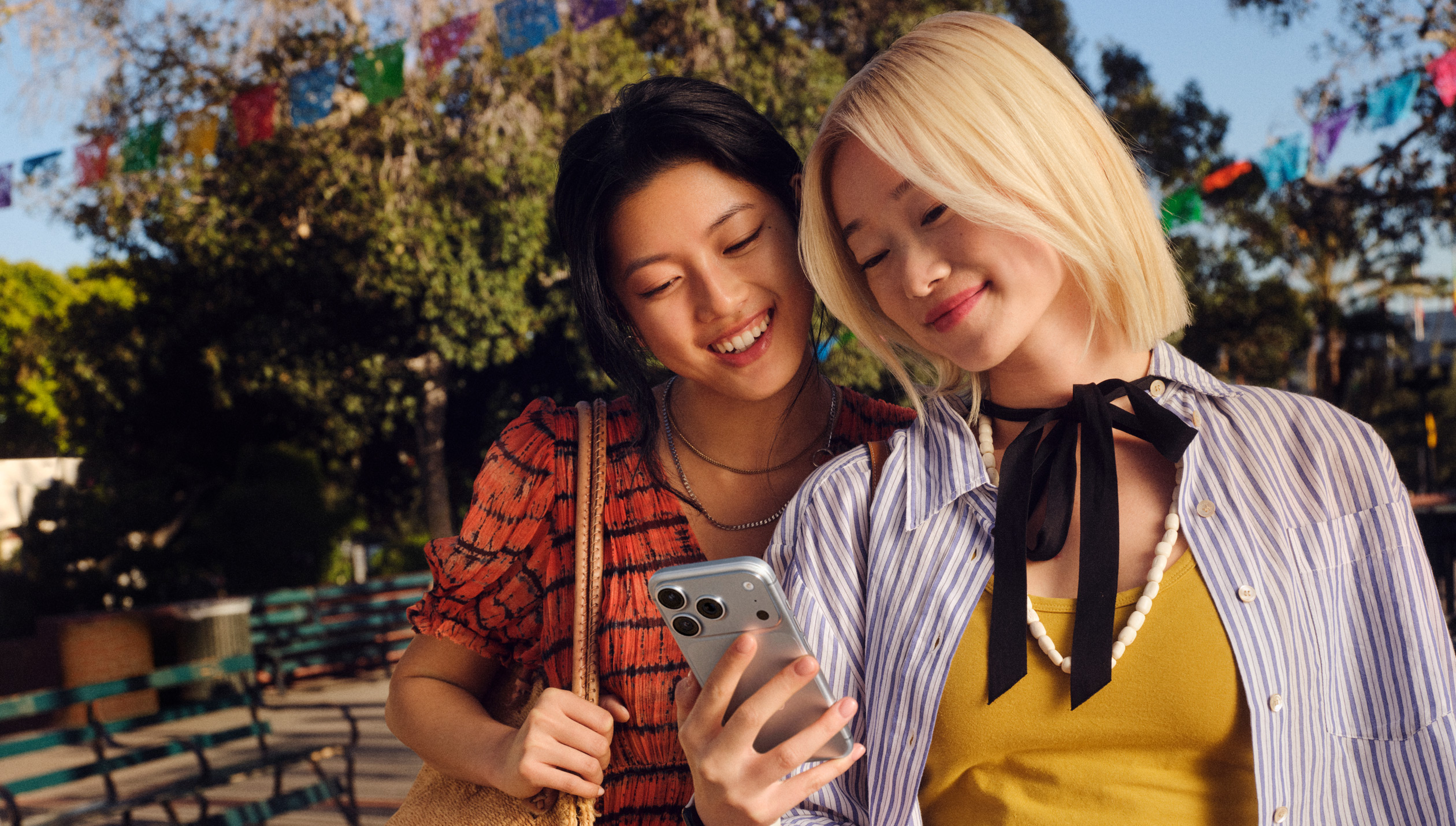 两人并肩站在洋溢着节日气氛的小镇街头，一起看着一台 iPhone。