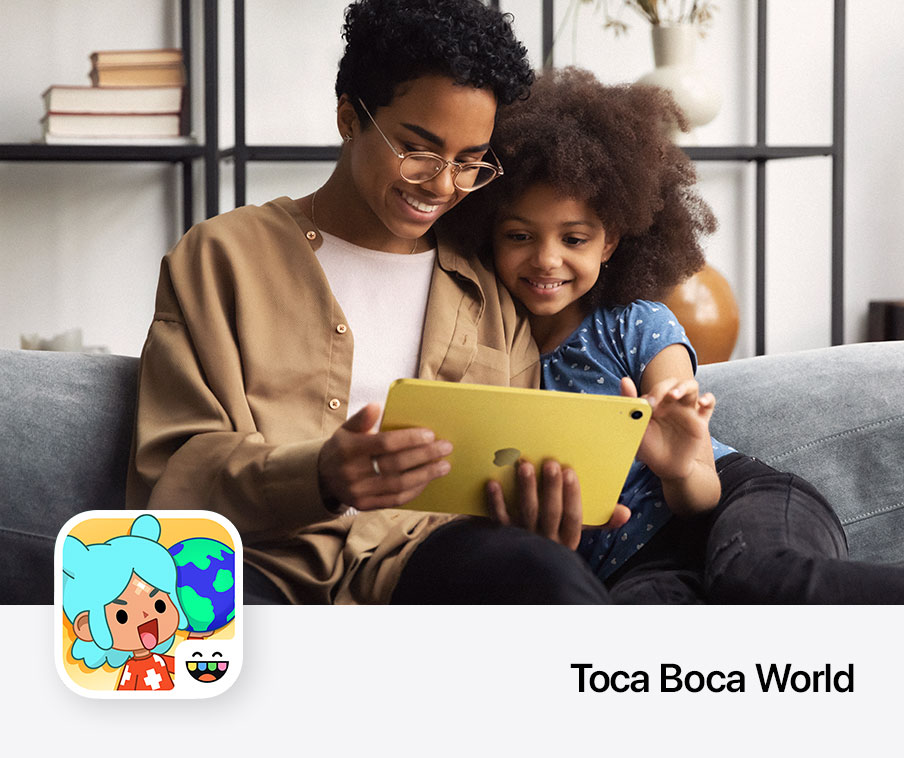 An adult and a child sitting on a couch looking at an iPad together.