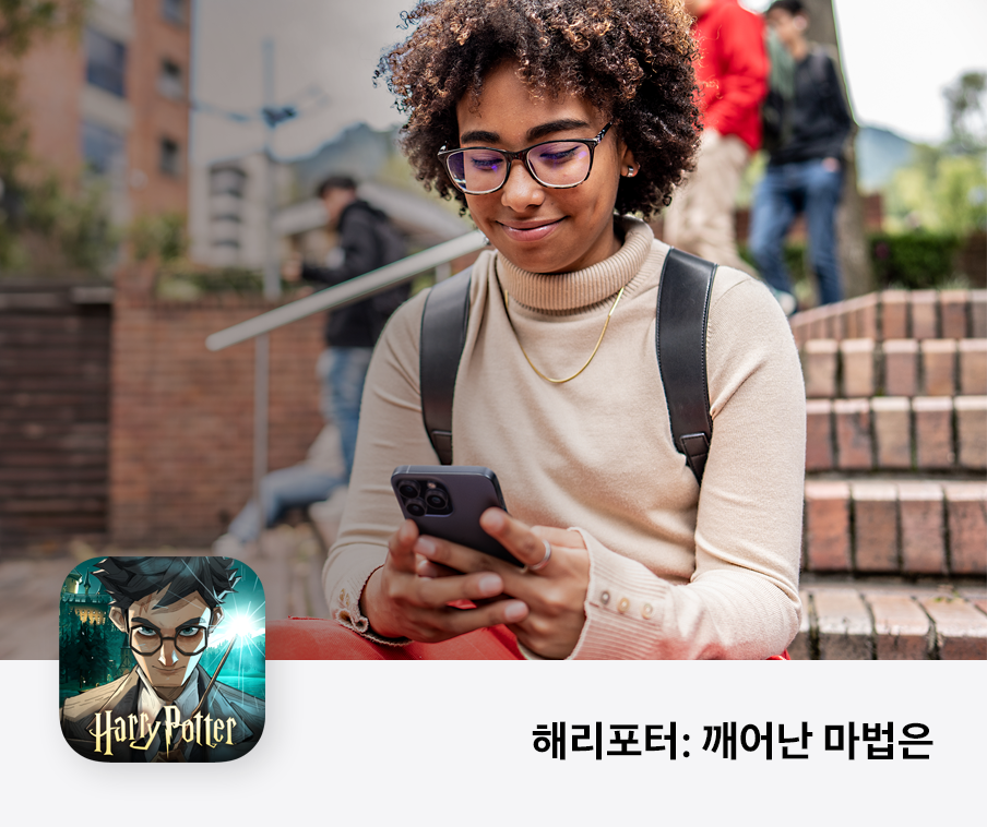 한 사람이 iPhone으로 게임을 플레이하면서 미소를 짓습니다.