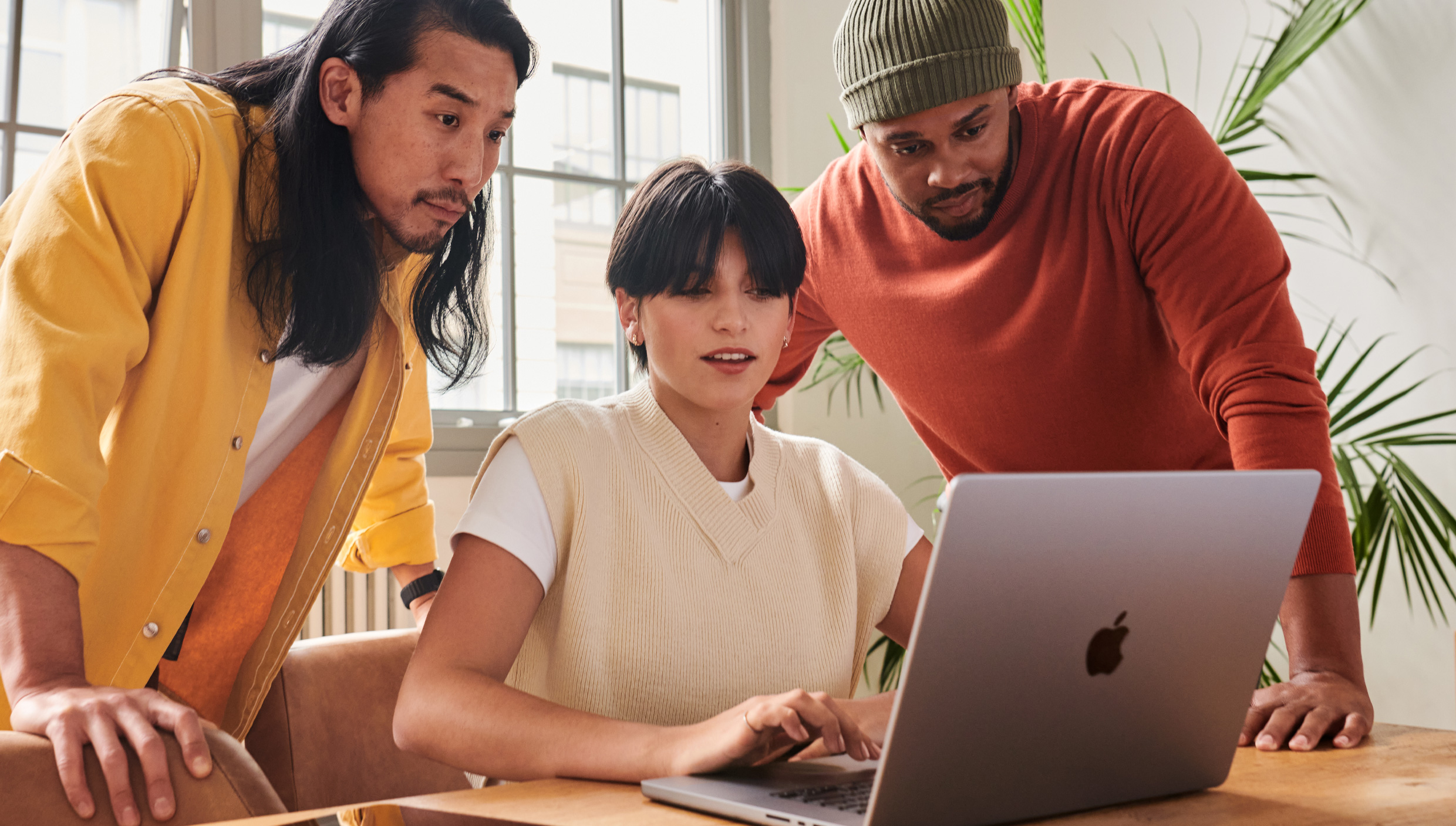 A team of three people working together on a computer.