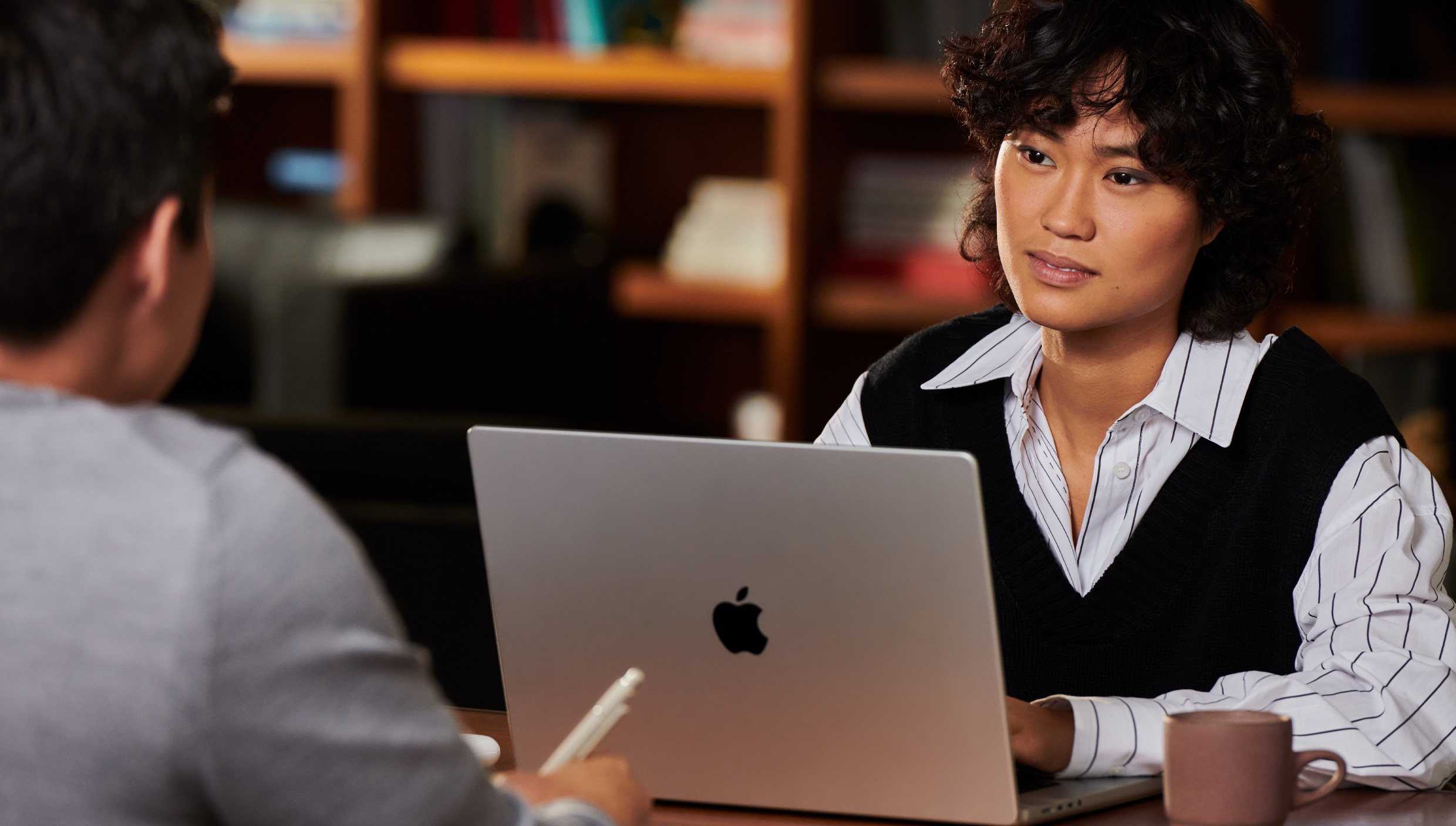 Comercializador trabajando en un Mac frente a un compañero de equipo.