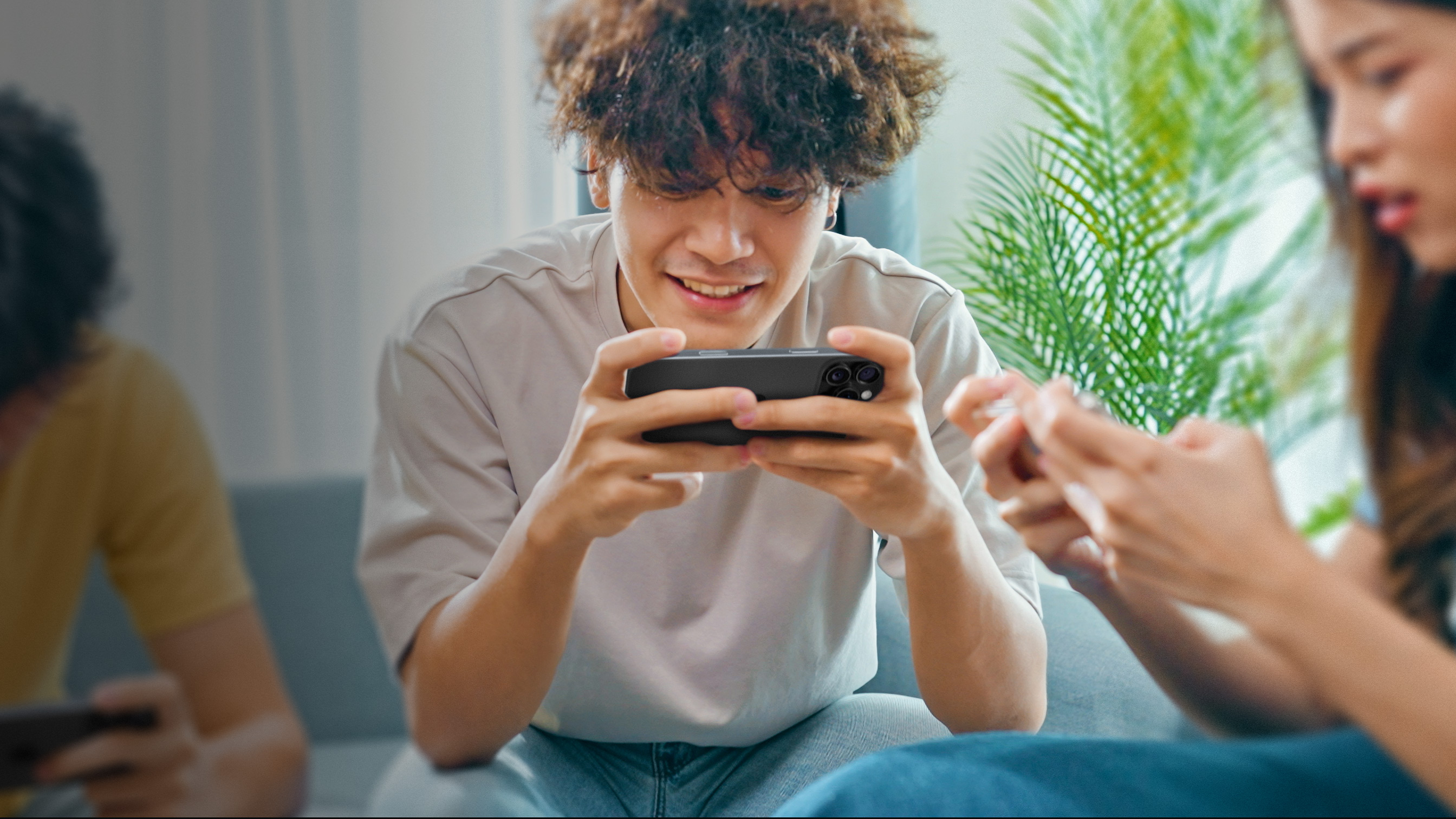 A person holding an iPhone, looking closely at the screen as they play a game.